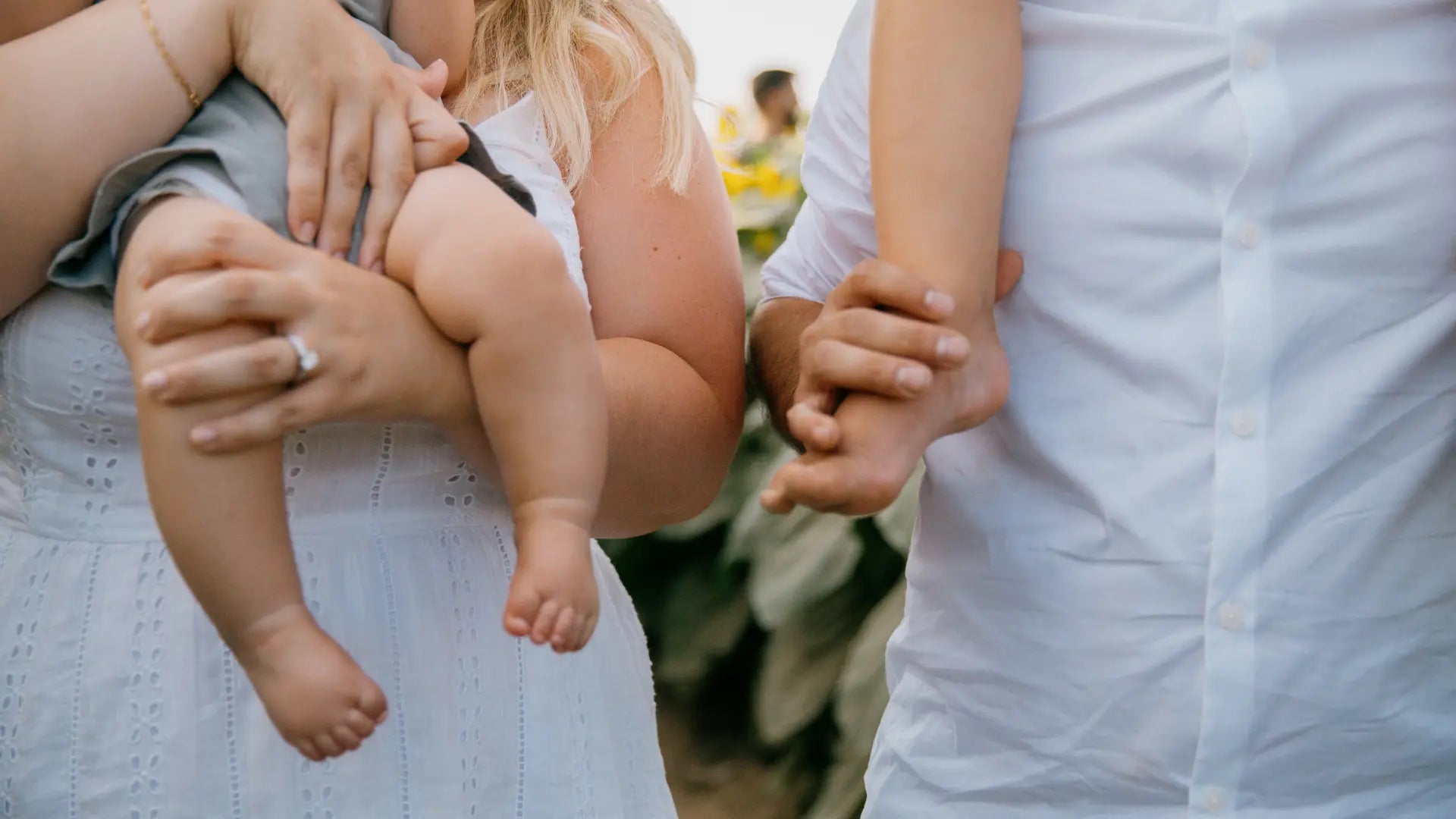 Parent tenant tendrement son enfant en écharpe porte-bébé, avec un sac à langer élégant au dos – une scène de vie douce, pratique et inspirante pour jeunes familles.