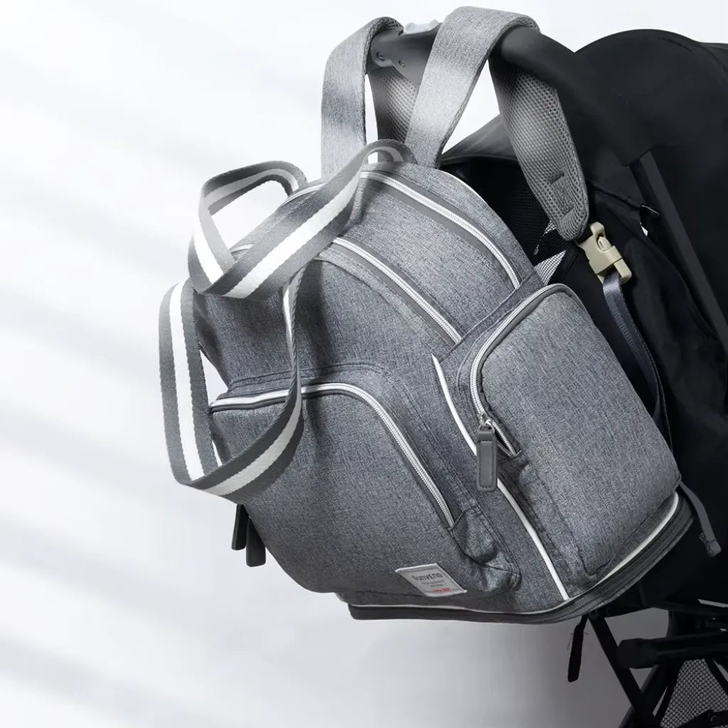 Sac NomadGlow posé sur une valise, illustrant son mode voyage grâce à la sangle arrière.