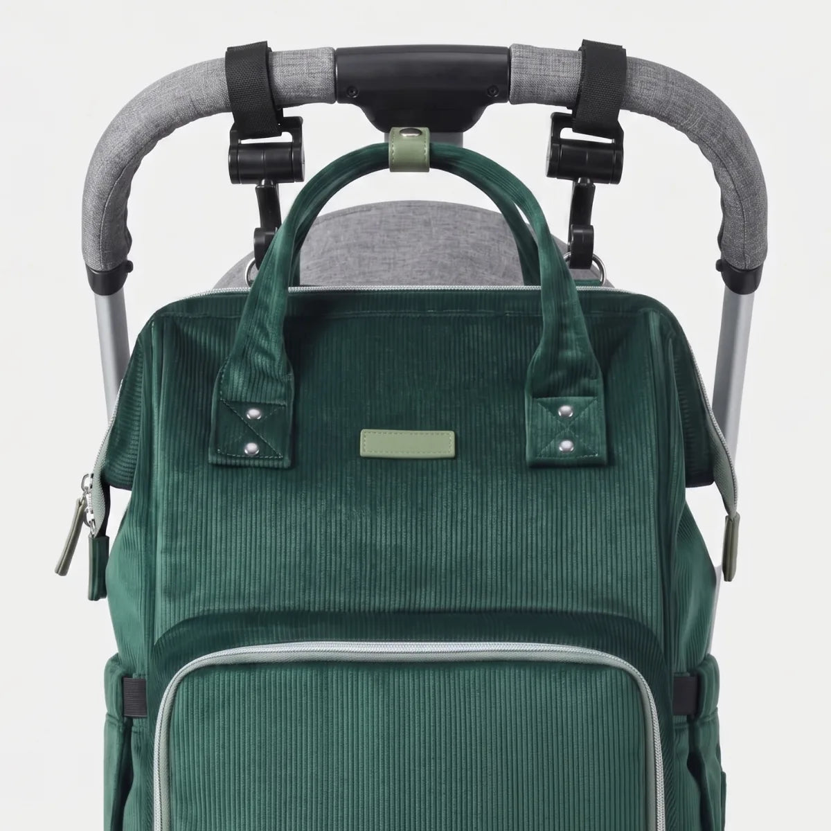 Sac à langer suspendu à une poussette avec crochets universels inclus montrant l'installation pratique pour les sorties en famille.