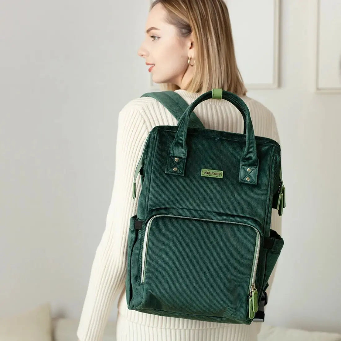 Maman portant son bébé avec le sac à langer velour côtelé tapis inclus et assorti, sur l’épaule, en balade