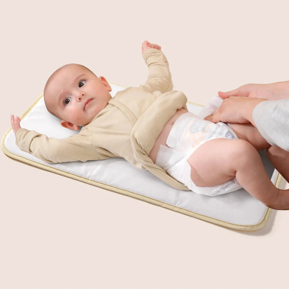 sac à langer moka posé ouvert avec accessoires bébé visibles

