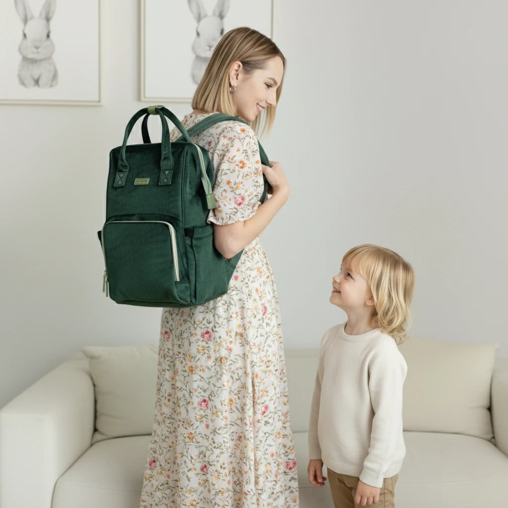 Maman portant un sac à langer en tissu premium, élégant et pratique, avec plusieurs rangements pour bébé.

