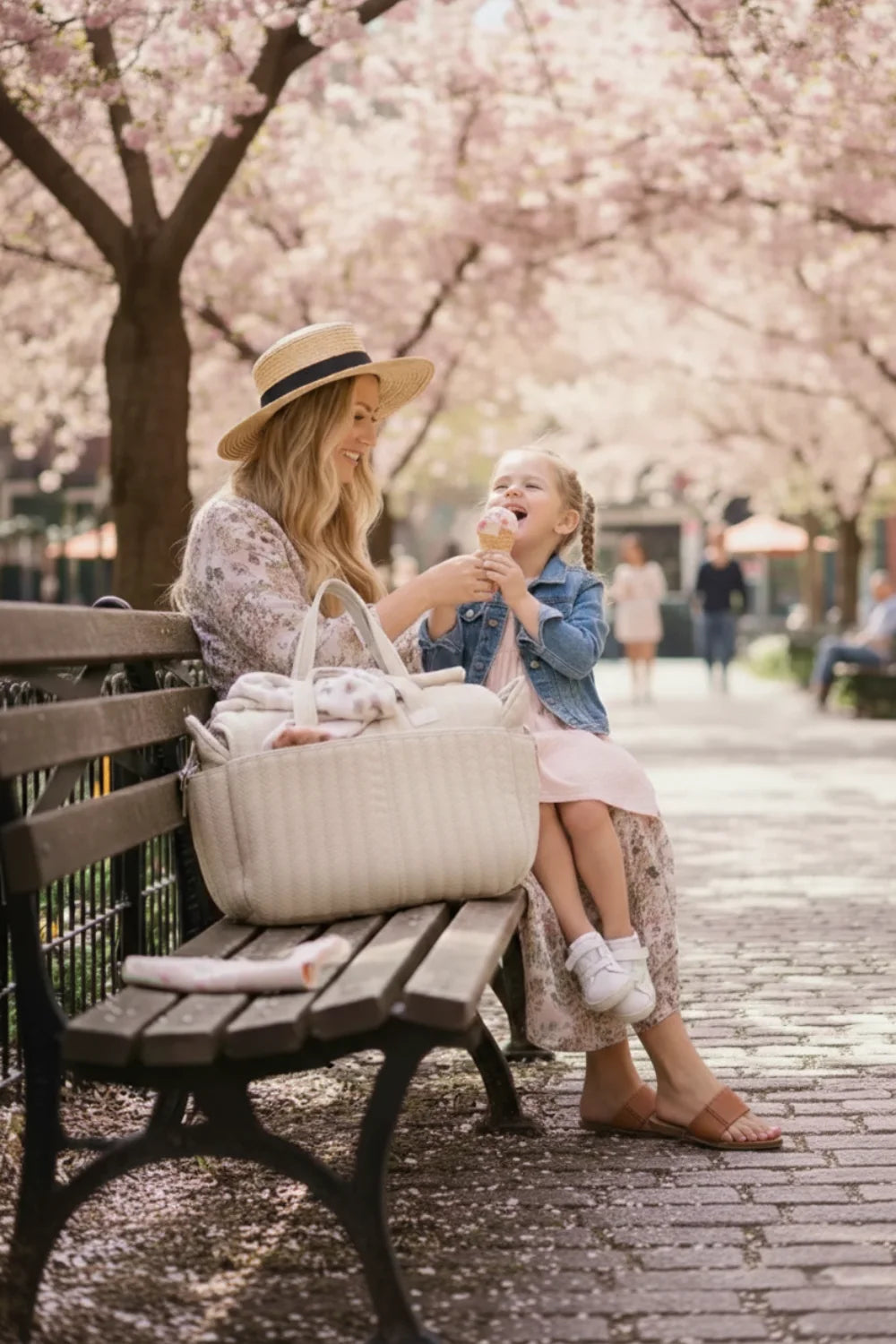 Maman élégante portant le sac à langer CozyTote en coton gaufré matelassé lors d'une promenade avec une poussette.
