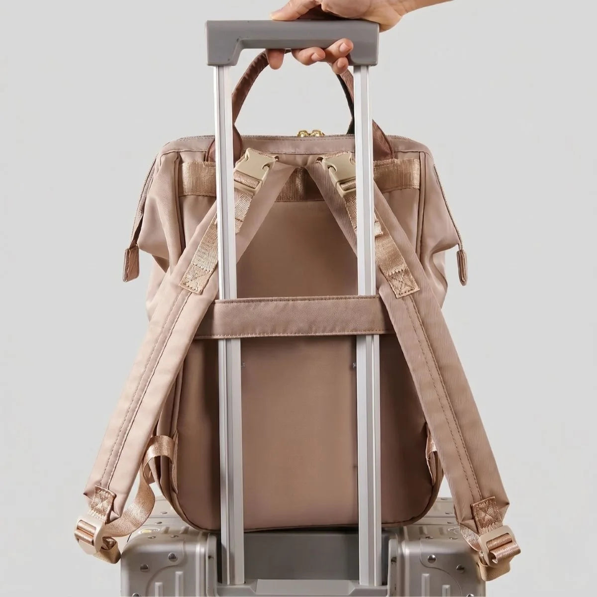 Sac à langer Moka fixé sur une valise cabine grâce à sa sangle de voyage intégrée.