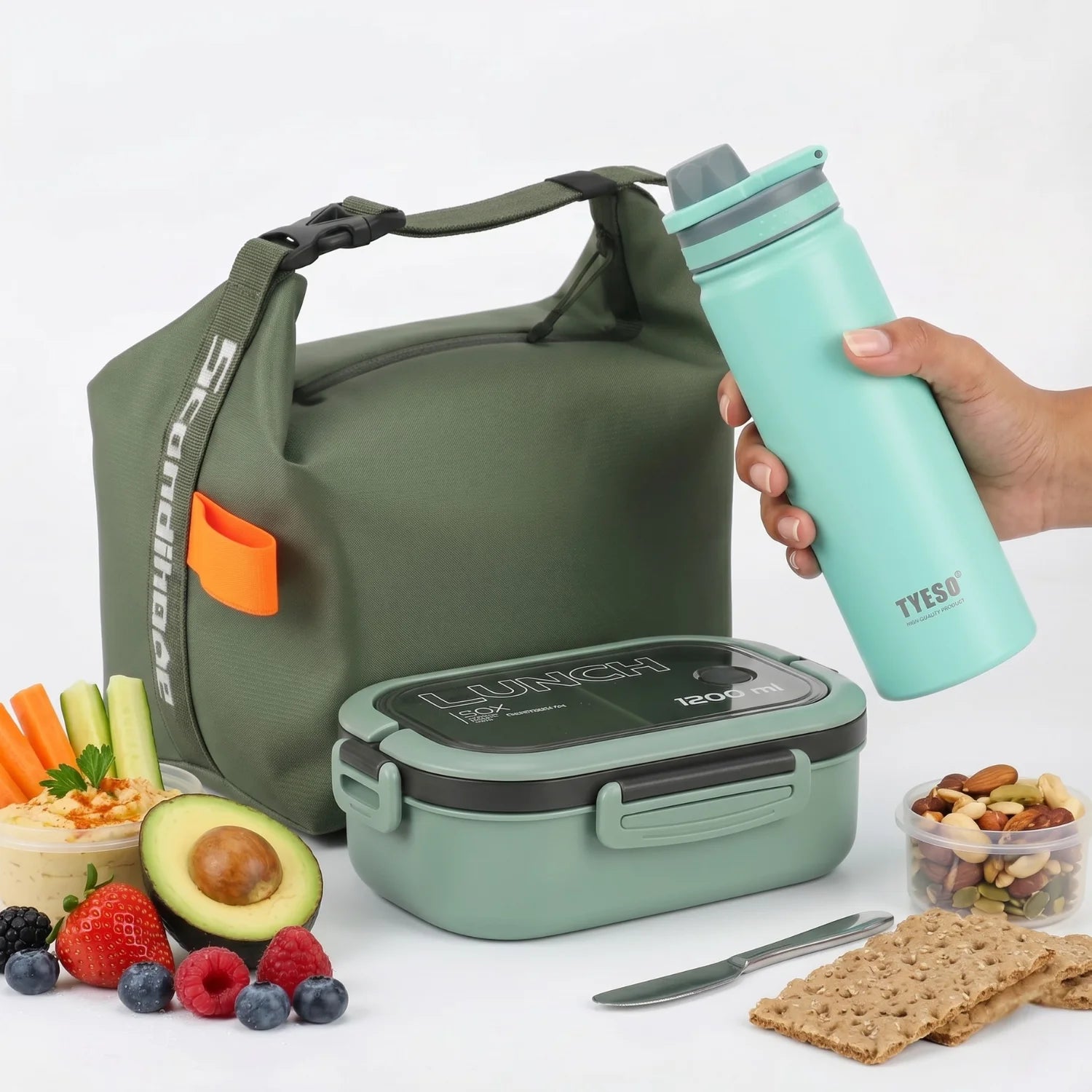 Une photographie professionnelle du pack Goodn'Lunch, un ensemble complet pour déjeuners nomades. Il comprend, de gauche à droite, un sac isotherme NomadBox de couleur vert kaki, compactable (26x15 cm), en tissu Oxford avec fermeture enroulable. Au centre, une bento box Snack&Go de 1200 ml, en plastique PP vert, avec compartiments et étanchéité renforcée. À droite, une gourde isotherme de 530 ml en acier inoxydable recyclé vert, avec poignée pliable, double paroi et étanche. L'ensemble est disposé sur un fo