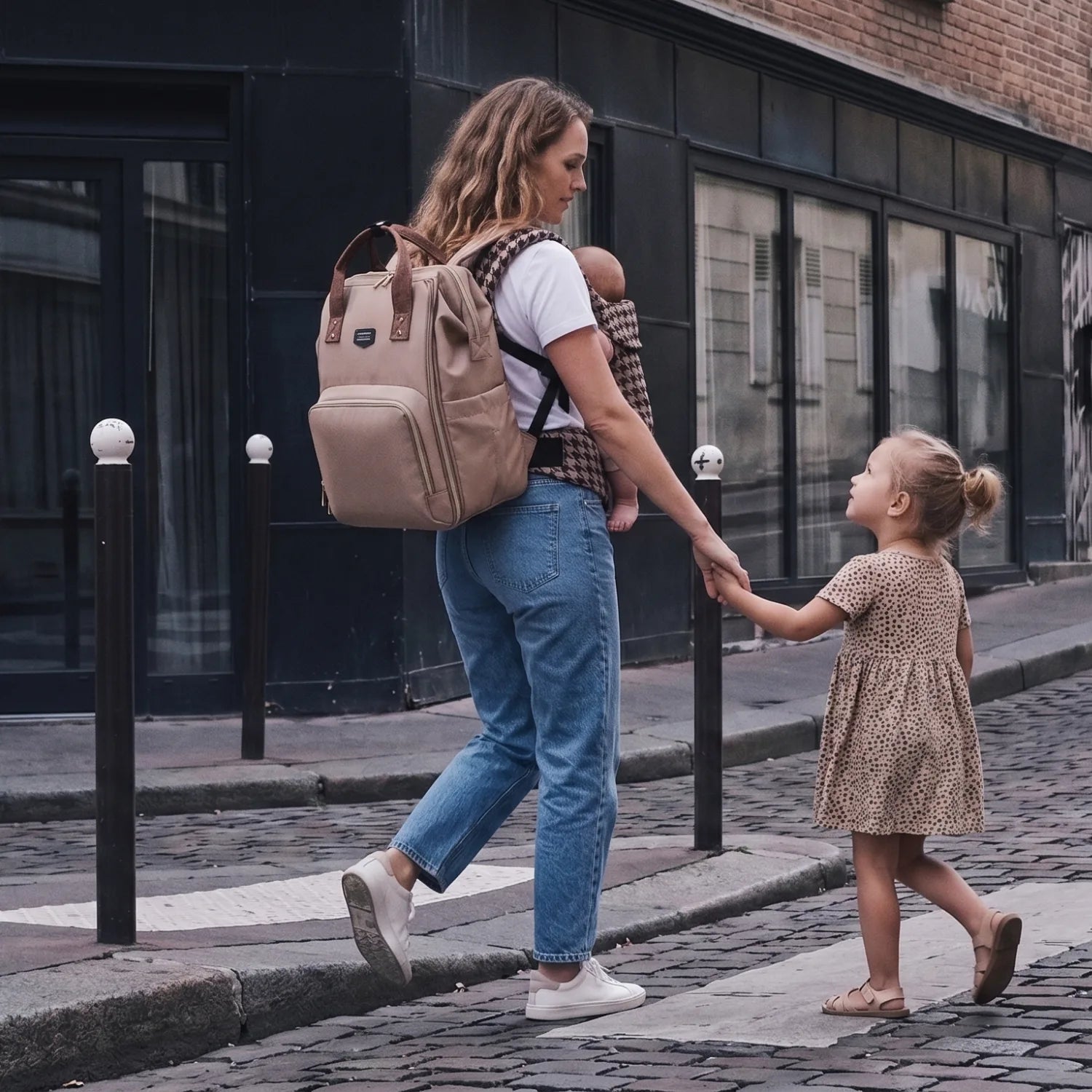 Maman en balade citadine avec sa fille, équipée du sac à langer Moka et du porte-bébé ergonomique HarmoBaby, composants du Pack Tribu Goodnvibes pour des sorties familiales stylées et organisées