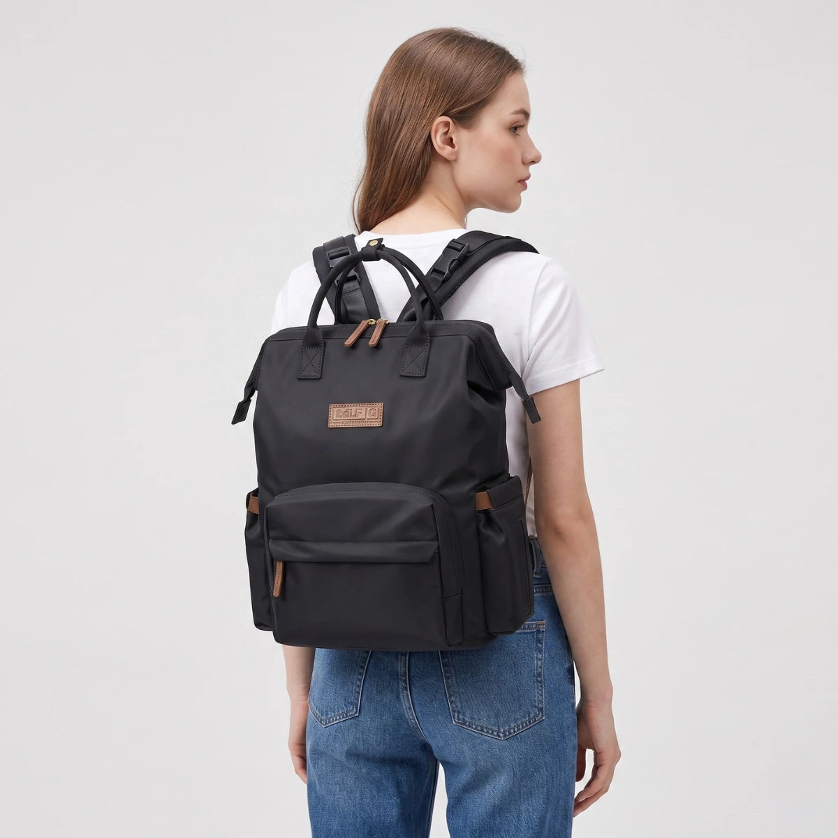 Sac à langer Nyla noir porté au dos par une maman active pour illustrer son design ergonomique et urbain.
